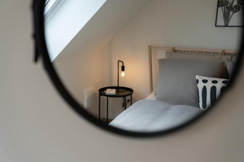 a bedroom with a bed and a round mirror at Küstenbutze im modernen Style mit Balkon in Mildstedt