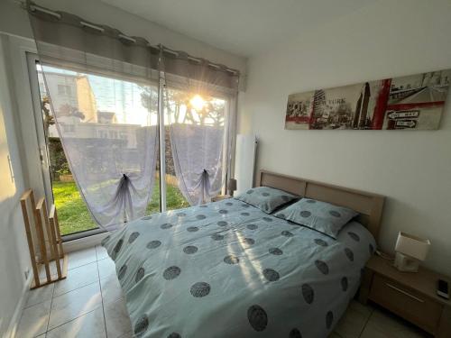 une chambre avec un lit et une grande fenêtre dans l'établissement Logement plein centre royan, à Royan