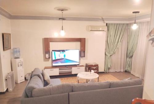 a living room with a couch and a flat screen tv at 2 Bedrooms Spacious flat 7 mins to Airport in Cairo