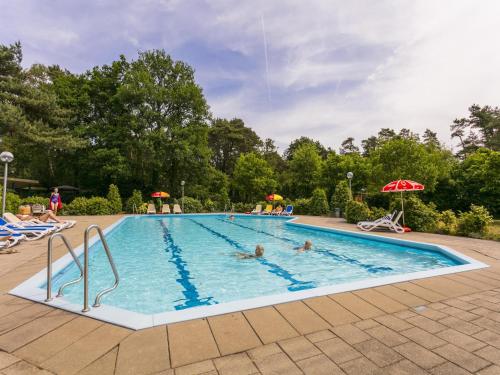 a large swimming pool with people in it at Chalet by Forest Edge with Modern Design in Markelo
