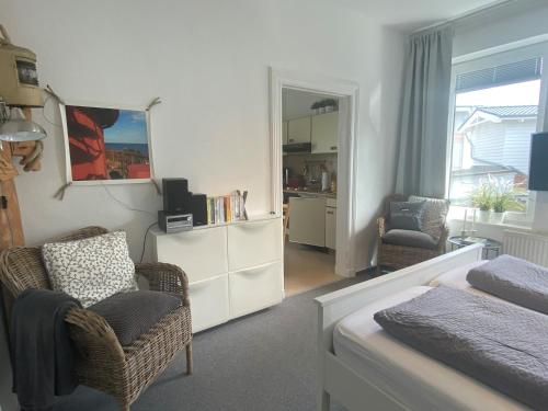 a bedroom with a bed and two chairs and a mirror at Haus AchternDiek Strandvogel in Dahme