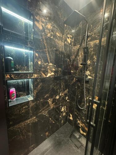 a bathroom with a shower with a black marble wall at Luxury 3bed Hot Tub and sauna facilities amazing location in Birmingham