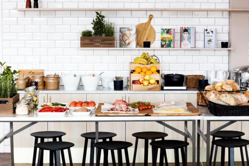 a kitchen with a counter with some food and stools at Welcome Hotel Barkarby in Järfälla
