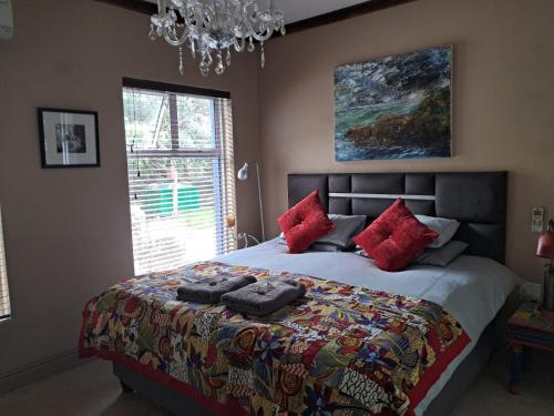 a bedroom with a large bed with red pillows at Listening Wind Self-Catering accommodation in Bettyʼs Bay