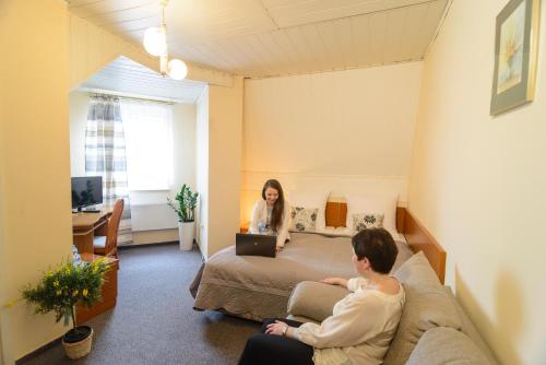 two people sitting on a bed in a hotel room at Hotel Dana in Bytów
