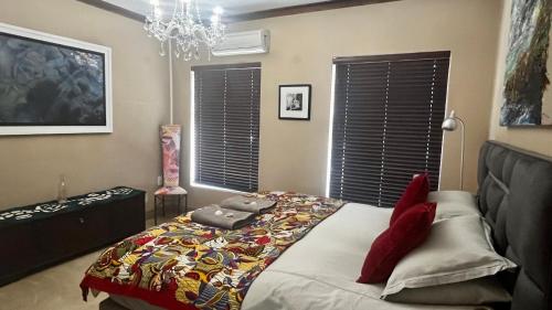 a bedroom with a bed with a quilt on it at Listening Wind Self-Catering accommodation in Bettyʼs Bay