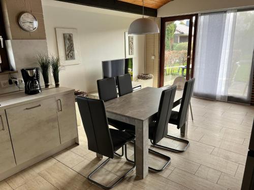 a dining room with a table and black chairs at Bungalow 6060 in Tossens in Tossenserdeich