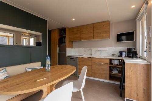 a kitchen with a wooden table and white chairs at Boje 70 in Scharbeutz