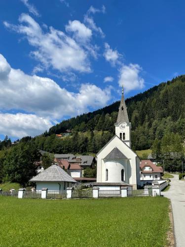 a white church with a steeple on a green field at Wiedweg Gold in Patergassen