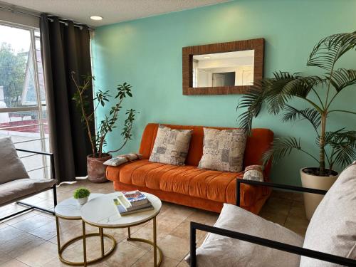 a living room with an orange couch and a mirror at Condesa, Depto 2 recamaras. in Mexico City