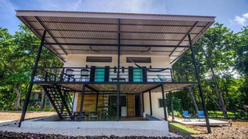 a house with a metal roof and a balcony at Casa Del Oeste, Playa Avellanas Beach House in Playa Avellana