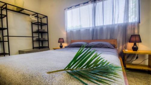 a bedroom with a bed with a palm plant on it at Casa Del Oeste, Playa Avellanas Beach House in Playa Avellana