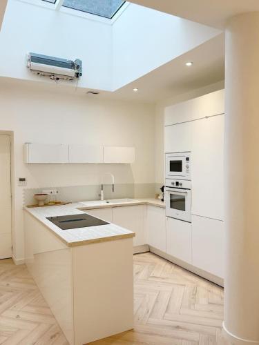 une cuisine avec des placards blancs et un plafond dans l'établissement Capsule Candy - piscine à boules - cinéma privé, à Roubaix