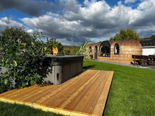 un patio trasero con terraza de madera y un edificio en Tirolian Lodge East, en Bundorf