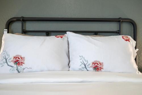 a bed with white pillows with red flowers on it at Tumbleweed charm of the Bus Stop Saloon in Cave Creek
