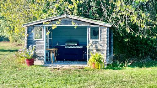 a small shed with a grill in a yard at Relais de La Brande in Saint-Gourson