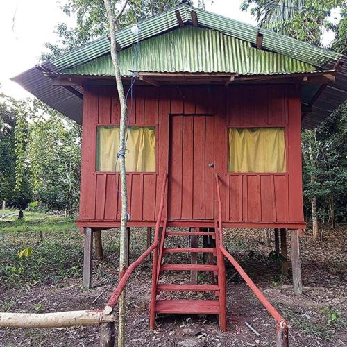 a red tree house with a ladder in front of it at Antares Jungle Lodge in Miraflores