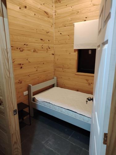 a small room with a bed in a wooden cabin at Twin Brothers Pichidangui 2 in Pichidangui