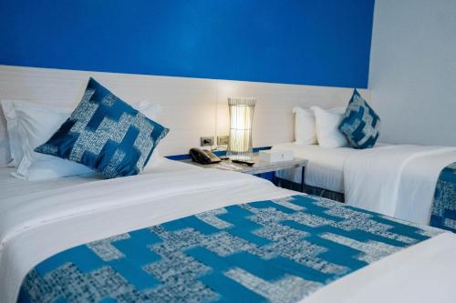 a hotel room with two beds and a blue wall at Stacia Hotel in Cebu City