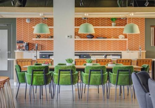 a dining room with a table and green chairs at Salt City Penthouse in Salt Lake City