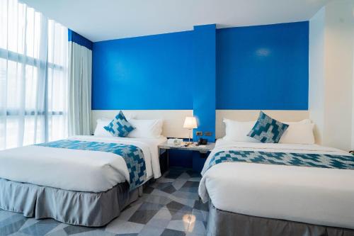 two beds in a room with blue walls at Stacia Hotel in Cebu City
