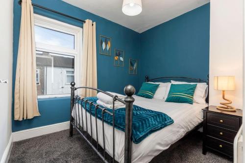 a blue bedroom with a bed and a window at The Terrace by the Market in Guisborough