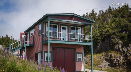 a house with a red door and a balcony at Boat House Loft in Port Rexton