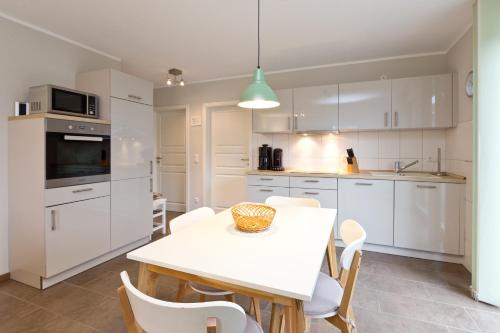 eine Küche mit weißen Schränken und einem Tisch und Stühlen in der Unterkunft Stieglitz Nest in Marienfelde