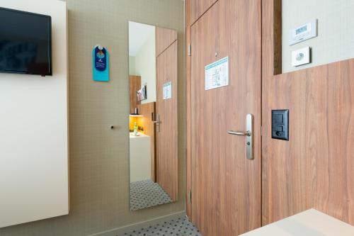a bathroom with a wooden door and a mirror at Hotel Wartmann am Bahnhof in Winterthur