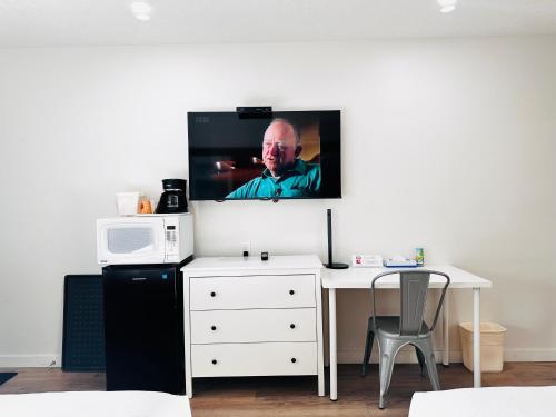 a tv hanging on a wall above a white desk at Cloud 9 Inn in Whitecourt