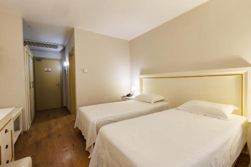 a bedroom with two beds and a hallway with a door at Riverside rooms at Hotel Fieri in Fier