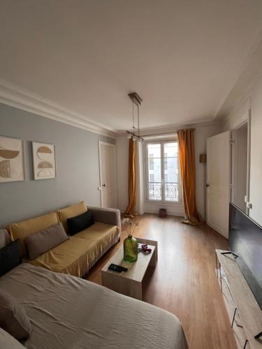 un salon avec un canapé et une table dans l'établissement Charming and cosy apartment, à Paris