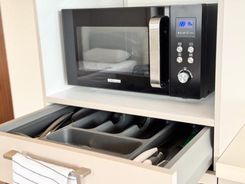 a microwave oven above a sink in a kitchen at modern living studios Karlsbad in Karlsbad