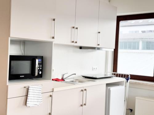 a white kitchen with a sink and a microwave at modern living studios Karlsbad in Karlsbad