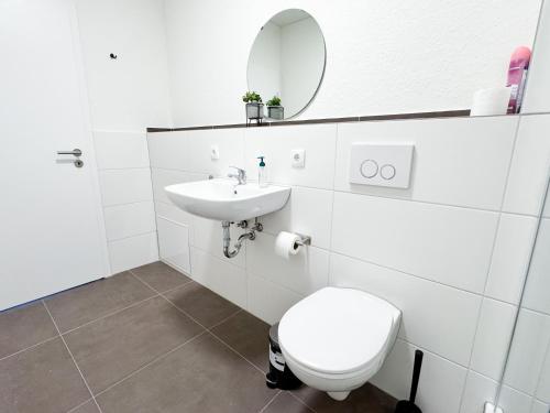a bathroom with a toilet and a sink and a mirror at modern living studios Karlsbad in Karlsbad