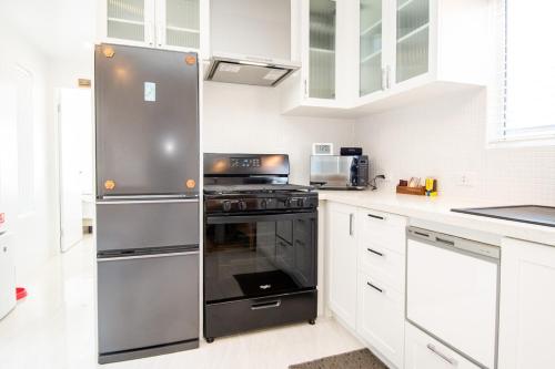 a kitchen with stainless steel appliances and white cabinets at Aotearoa House Yomitan, BBQ, Pizza Oven in Yomitan