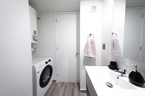 a white bathroom with a washing machine and a sink at Luxury con Vista en Irarrázaval - Estadio Nacional in Santiago