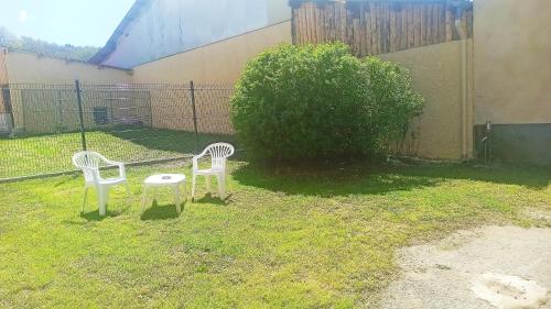 two white chairs and a table in a yard at La Maison du Livradois in Beurrières