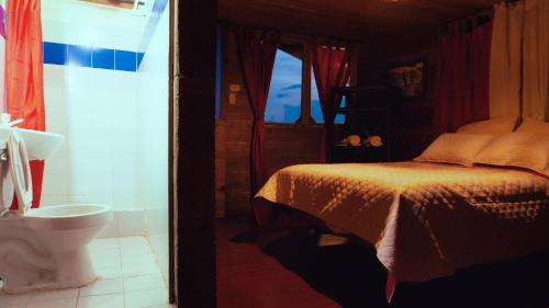 a bedroom with a bed and a bathroom with a toilet at Cabañas/glamping monaco in Santa Rosa de Cabal