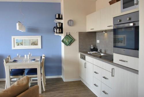 a kitchen with a small table and a kitchen with white cabinets at Apartment 29 "Heimathafen 29", Apartmenthaus Hafenspitze, Blickrichtung InnenstadtBinnenhafen in Eckernförde