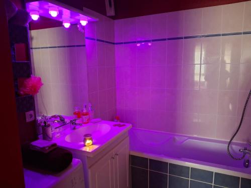 La salle de bains est pourvue d'un lavabo et d'une baignoire avec des lumières violettes. dans l'établissement Le plaisir du calme, à Limoges