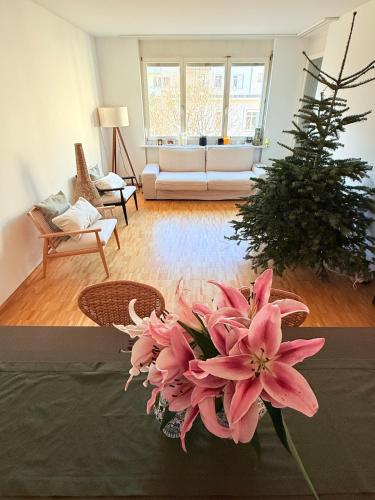a living room with a bouquet of pink flowers on a table at Very nice flat 80 meter from SBB in Basel
