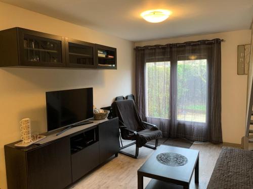 ein Wohnzimmer mit einem Flachbild-TV und einem Stuhl in der Unterkunft Petit cottage à 3 minutes à pied de la plage avec terrasse et Parking privée gratuit in Blonville-sur-Mer