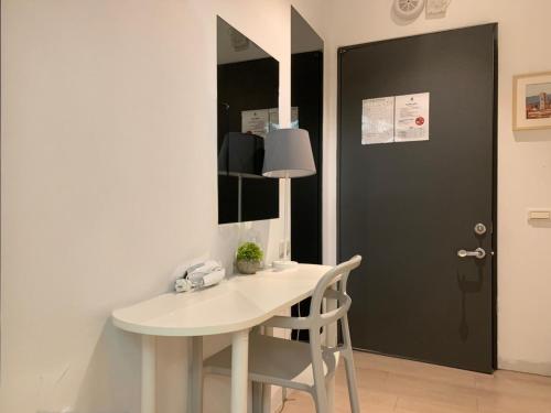 a white table and chair in a room with a door at Bluewater Hotel Xpark Gloria Outlets Taoyuan Baseball Stadium in Dayuan