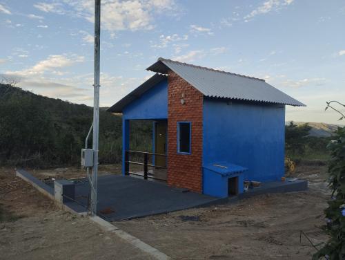 a small blue and red building in a field at Chalé da Pousada Avalon Célia in Alto Paraíso de Goiás