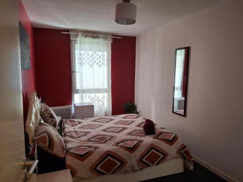 - une chambre avec un lit aux murs rouges et une fenêtre dans l'établissement Le plaisir du calme, à Limoges