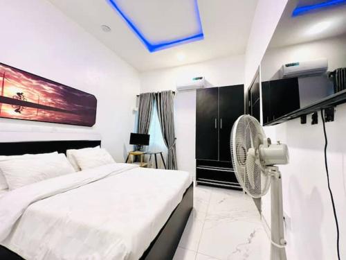 a bedroom with a white bed and a fan at Fabulous 2 Bedroom Flat in Iju Junction