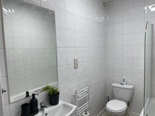 a white bathroom with a toilet and a sink at Cosy 2 bed Wimbledon Apartment in Raynes Park