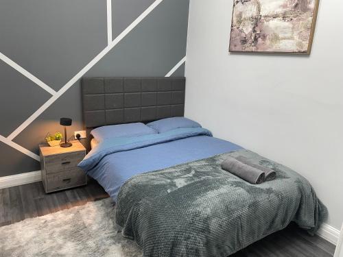 a bedroom with a bed with a blue comforter at Cosy 2 bed Wimbledon Apartment in Raynes Park