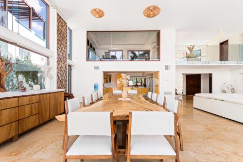 Un comedor con una mesa de madera y sillas blancas. en Villa Azul Maya, en Isla Mujeres